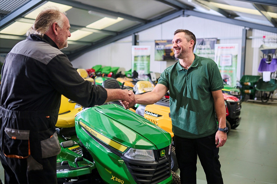 Professional landscaper shaking hands and smiling with salesman at a garden machinery dealer